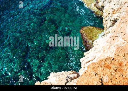 Hintergrund der gelben und weißen Sandstein in der Nähe von transparenten plätscherte Kristallklares erstaunlich grünen Wasser. Warme wolkenlosen Sommertag. Stockfoto