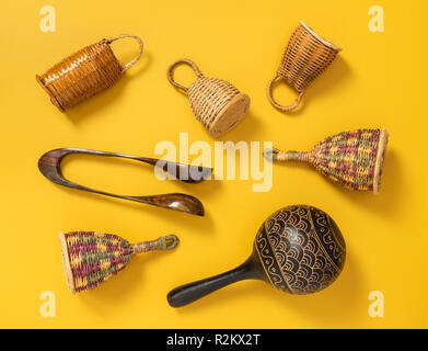 Holz- percussion Musikinstrumente auf gelben Hintergrund. Caxixi Shaker, Maracas und musikalische Löffel. Stockfoto