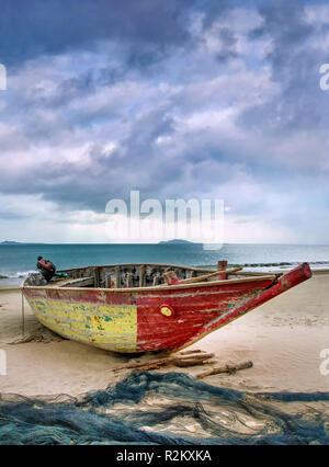 Old wooden Fisher-Boot an einem bewölkten Strand, Sanya, China. Stockfoto