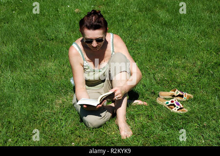 ältere Frau liest auf der Wiese Stockfoto