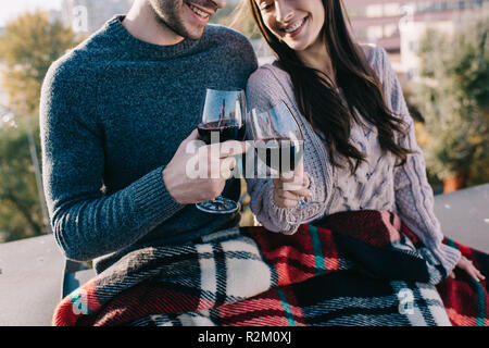 7/8 Schuß von schönen jungen Paar in Plaid und trinken Rotwein auf dem Dach Stockfoto