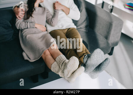 7/8 Schuß von Paar in warme Wollsocken entspannen auf der Couch zu Hause Stockfoto