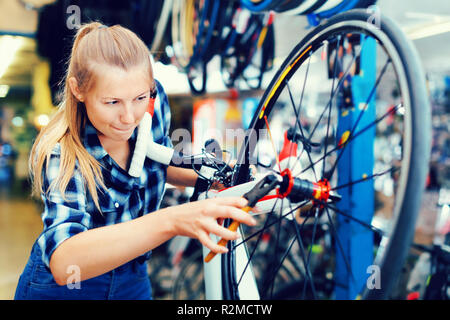 Portrait von Happy fröhliches Mädchen, arbeitet mit einer Zange und Befestigung der Räder in der Werkstatt. Stockfoto