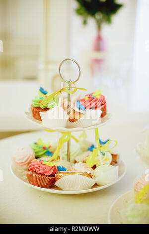 Mini chocolate Cupcakes mit Mini rosa Donuts auf ein Dessert Tisch lagen. Sie sind auf eine mehrstufige Anzeige fach Gourmet Cupcakes mit bunten buttercream angezeigt. Candy Bar. Selektive konzentrieren. Getonten Bild Stockfoto