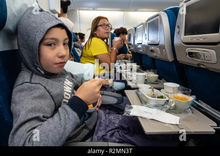 Eine Familie essen eine Mahlzeit an Bord eines Flugzeugs auf einem Langstreckenflug in Urlaub zu fahren. Stockfoto