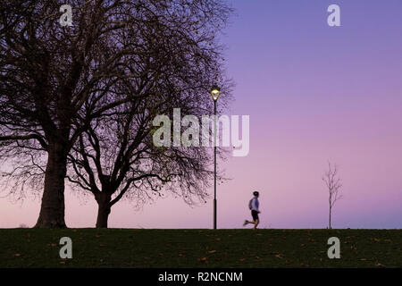 Person joggen. Mann laufen oder Training in einem Park bei Nacht, Nottingham, England, Großbritannien Stockfoto