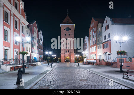 Altstadt von Elbing, Polen in der Nacht. Renovierte Häuser auf Stary Rynek Straße mit mittelalterlicher Markt Tor (polnisch: Brama Targowa). Stockfoto