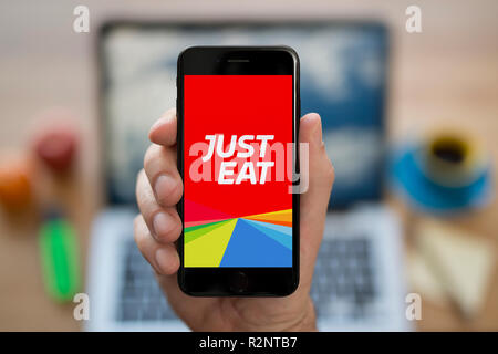 Ein Mann schaut auf seinem iPhone die zeigt die Nur Essen, Logo, während saß an seinem Computer Schreibtisch (nur redaktionelle Nutzung). Stockfoto