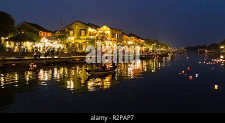 Beleuchtete, historischen Hoi An Altstadt am Abend, von der Brücke, Reflexionen von Leuchten, Boot und schwimmende Kerzen auf dem Wasser, Panorama Stockfoto