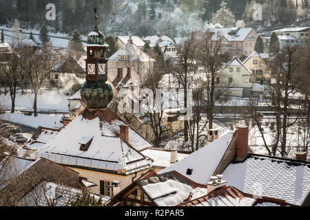 Blick auf verschneite Stadt Häuser mit rauchenden Schornsteine, von oben, Murau, an einem sonnigen Wintertag Stockfoto