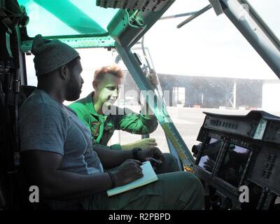 Us Marine Kapitän Steve Vining, ein Pilot mit Marine Light Attack Helicopter Squadron 367, zeigt Schauspieler Stephen Hill um Ein UH-1Y Huey Hubschrauber, auf Marine Corps Base Hawaii, November 2, 2018. Hügel spielt eine ehemalige Marine Huey Pilot als Theodore 'TC' Calvin auf der TV-Serie Magnum P.I. Stockfoto