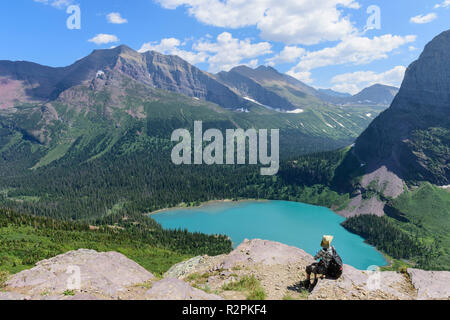 Wanderer, die sich auf Rock der Anwendung Sun Lotion auf Grinnel Glacier Trail, Glacier National Park, Montana Stockfoto