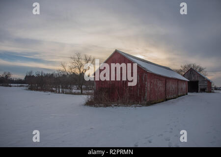 Wisconsin, United States-February 11,2017: Rustikale rote Ställe bei Sonnenuntergang in Ackerland Einstellung in Wisconsin, Vereinigte Staaten Stockfoto