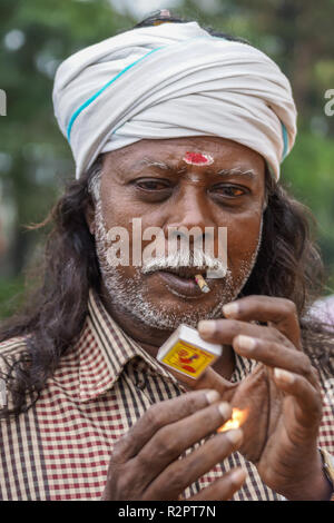 Angadihalli, Karnataka, Indien - November 2, 2013: Nahaufnahme von bärtigen Mann mit weissen Turban und kariertem Hemd Beleuchtung seiner beedi Zigarette mit einem Stockfoto