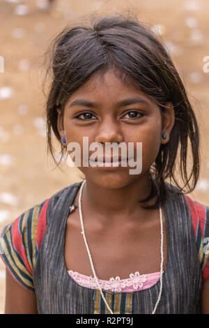 Angadihalli, Karnataka, Indien - November 2, 2013: Nahaufnahme von jungen Mädchen mit schwarzen Haaren und blauen Stifte in Ihren Ohren lächeln und trägt bunte Hemd und Stockfoto