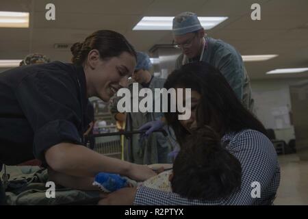 PAITA, Peru (Nov. 1, 2018) - Lt. j.g. Janine Swanson, aus Rochester, N.Y., Kontrollen auf den Patienten und seine Mutter nach der Operation im Aufwachraum (AUFWACHRAUM) an Bord des Hospital Ship USNS Comfort (T-AH 20). Komfort ist auf einem 11-Woche medizinische Unterstützung Mission in Zentral- und Südamerika als Teil des US Southern Command's Enduring Promise Initiative. Arbeiten mit Gesundheit und Regierung Partner in Ecuador, Peru, Kolumbien und Honduras, die EINGESCHIFFTEN medizinisches Team kümmert sich an Bord und an Land-basierte medizinische Websites, wodurch der Druck auf die nationalen medizinischen Systemen teilweise verursacht zu entlasten Stockfoto