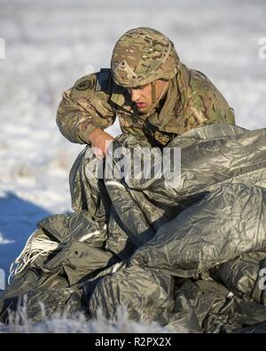 Armee Kapitän Jordanien Robinson, in D Unternehmen zugewiesen sind, 6. Brigade Engineer Brigade Engineer Battalion, 4th Infantry Brigade Combat Team (Airborne), 25 Infanterie Division, U.S. Army Alaska, erholt sich sein Fallschirm nach Springen von einem CH-47 Chinook Hubschrauber Joint Base Elmendorf-Richardson, Alaska, November 1, 2018. Die Soldaten der 4/25 gehören zu den nur American Airborne Brigade im Pazifik und sind geschult in der Luft Manöver bei extrem kalten Wetter und Höhenlage Umgebungen zur Unterstützung der Bekämpfung, Partnerschaft und Katastrophenhilfe Operationen auszuführen. Heeresflieger aus der B-Company, 1. Batt. Stockfoto