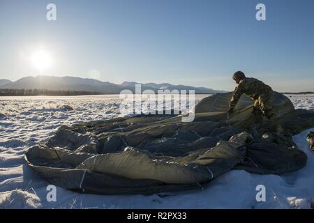 Ein Heer Fallschirmjäger in die 4 Infantry Brigade Combat Team (Airborne), 25 Infanterie Division, U.S. Army Alaska zugeordnet, erholt sich sein Fallschirm nach Springen von einem CH-47 Chinook Hubschrauber Joint Base Elmendorf-Richardson, Alaska, November 1, 2018. Die Soldaten der 4/25 gehören zu den nur American Airborne Brigade im Pazifik und sind geschult in der Luft Manöver bei extrem kalten Wetter und Höhenlage Umgebungen zur Unterstützung der Bekämpfung, Partnerschaft und Katastrophenhilfe Operationen auszuführen. Heeresflieger aus der B-Company, 1 Battalion, 52nd Aviation Regiment aus Fort Wainwright, Betrieben C Stockfoto