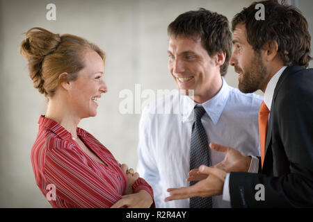 Blick auf eine Geschäftsfrau auf zwei Geschäftsmänner lächelnd. Stockfoto