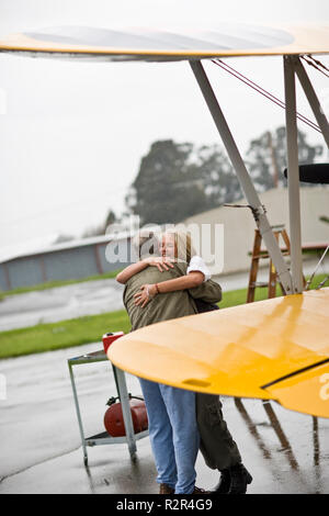 Mann und Frau umarmen neben Flugzeug Stockfoto