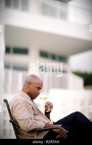 Mitte der erwachsene Mann schnüffeln ein Glas Wein am Gartentisch. Stockfoto