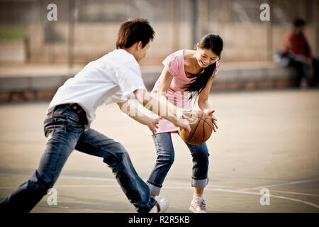 Junge erwachsene Paare spielen Basketball in einem Park. Stockfoto