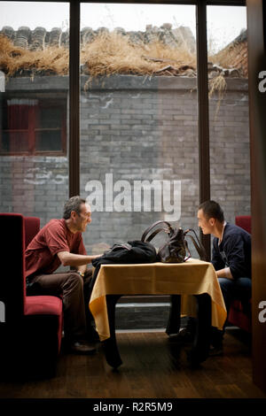 Zwei erwachsene Männer, die an einem Tisch in der Lobby zu sitzen. Stockfoto