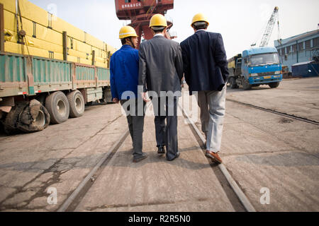 Gruppe von Geschäftsleuten Tragen von Schutzhelmen entlang eine Wharf. Stockfoto