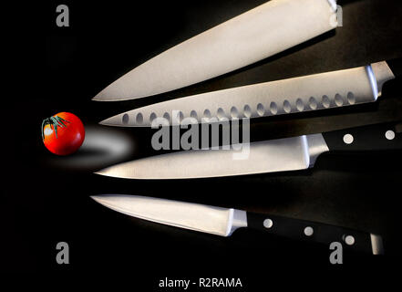 Verschiedene scharfe und glänzend Küche Messer sind mit einem kleinen Tomaten in diesem Foto gesehen. Stockfoto