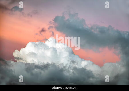 Stürmische Wolken sind hell durch die untergehende Sonne beleuchtet und von einem bunten Lachs Himmel gesichert. Stockfoto