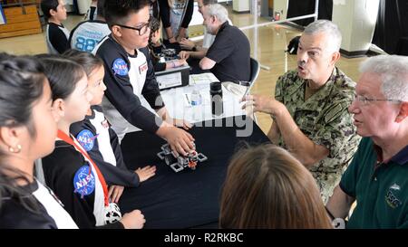 Chula Vista, Kalifornien (4. 3, 2018) Hintere Adm. Ron Fritzemeier, Center, Chief Engineer zu Raum und Naval Warfare Systems Command (Spawar) und Herr Bill Bonwit, Executive Director, Raum und Naval Warfare Systems Center Pacific interagieren mit Wettbewerbern auf die Inspektion Tabelle zugewiesen während des 10. jährlichen Mayfield High School/SPAWAR für Inspiration und Anerkennung von Wissenschaft und Technologie (ersten) LEGO League robotics qualifizierende Turnier. Mehr als 60 SPAWAR Freiwillige in die Veranstaltung unterstützt, Schiedsrichter, Richter, Timer und Mentoren. Erste Robotik Wettbewerbe kombinieren die Aufregung der Sport Stockfoto