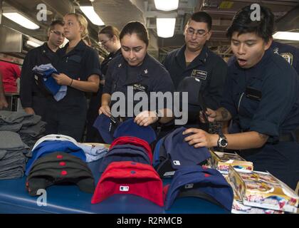 PEARL HARBOR (Nov. 4, 2018) Matrosen an Bord Arleigh Burke Klasse geführte Anti-raketen-Zerstörer USS Wayne E.Meyer (DDG108) erhalten die Erinnerungsstücke von Major League Baseball (MLB) Spieler während der Tour der Spieler von Joint Base Pearl Harbor-Hickam. Die MLB Spieler nahm auch an einer Vereinigten durch Lesen Veranstaltung durch das Lesen für die Kinder der Mitglieder. Stockfoto