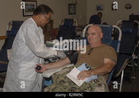 Kapitän Timothy Poe, Commander, Submarine Squadron (SUBRON) 15, spendet Blut während des U-Boots Squadron (SUBRON) 15 Blood Drive, Okt. 30. Blut spenden wurden von 16 Freiwilligen in Unterstützung der bewaffneten Dienstleistungen Blut Programm mobile Blood Drive akzeptiert von SUBRON 15 an Polaris Point gehostet werden. Stockfoto