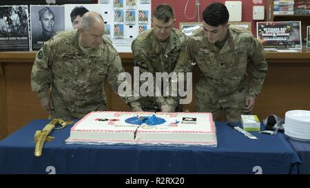 (Von links): 1 Sgt. Dennis Donlan, die älteste Soldat in der US-Army Central arbeiten, Oberst Christopher Coglianese, stellvertretender Stabschef der USARCENT, und SPC. Spencer Post, der jüngste Soldat derzeit an USARCENT, schneiden Sie einen Kuchen der 3. Armee Centennial in Camp Arifjan, Kuwait, Nov. 7, 2018 zu feiern. Feiern wie diese fördern Espirit de Corps und Stolz in Geschichte für die Soldaten, die derzeit in der 3. Armee. Stockfoto