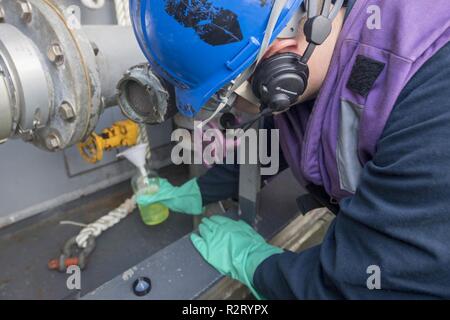 EAST CHINA SEA (Nov. 9, 2018) Gas Turbine System Technician (mechanisch) Feuerwehrmann Thomas Tate, aus Houston, Texas, nimmt eine F-76 Kraftstoff Probe für die Inspektion auf der Ticonderoga-Klasse geführte-missile Cruiser USS Chancellorsville (CG62) während einer Auffüllung-auf-See mit dem Militär Sealift Command flotte Auffüllung öler USNS Tippecanoe (T-AO 199). Chancellorsville ist Vorwärts - in die USA 7 Flotte Bereich für Maßnahmen zur Erhöhung der Sicherheit und Stabilität in der indopazifischen Region bereitgestellt. Stockfoto