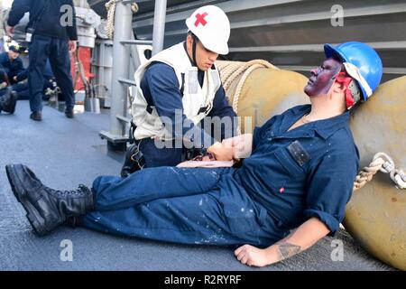 Mittelmeer (Nov. 7, 2018) - Hospital Corpsman 3. Klasse Brian Bello behandelt Seaman Kaleb Rhoads "simulierten amputierten Arm während einer Messe Unfallversicherung bohren an Bord der Arleigh-Burke-Klasse geführte Anti-raketen-Zerstörer USS Ross (DDG71) im Mittelmeer, November 7, 2018. Ross, Vorwärts - Rota, Spanien bereitgestellt werden, wird auf der siebten Patrouille in den USA 6 Flotte Bereich der Maßnahmen zur Unterstützung der US-amerikanischen nationalen Sicherheitsinteressen in Europa und in Afrika. Stockfoto
