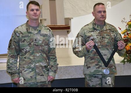 Sgt. Maj. David Clark, die US-Army Europe chief für religiöse Angelegenheiten Sergeant Major, stellt Personal. Sgt. Aaron Madasz, 2.Kavallerie Regiments, mit der ersten Staff Sgt. Christopher Stout Medal unterzeichnet durch den Leiter der Kapläne, November 7, 2018. Stockfoto