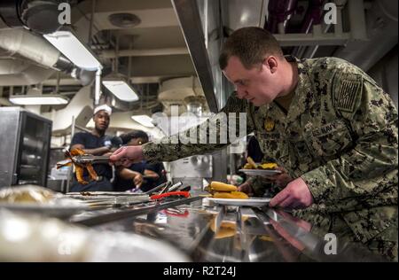 Atlantik (Nov. 07, 2018) Master-at-Arms 2. Klasse Vincent Stephens, von Nashville, Tennessee, Kleider seine Burger während einer Moral, Wohlfahrt und Erholung (MWR) Veranstaltung an Bord der Flugzeugträger USS George H.W. gefördert Bush (CVN 77). GHWB ist unterwegs in den Atlantischen Ozean die Durchführung von routinemäßigen Übungen Träger bereit zu halten. Stockfoto