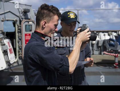 Gewässern vor der Küste von SAIPAN (Nov. 09, 2018) Operations Specialist 2. Klasse Austin Reid, Links, und Lt. j.g. Robert Lovejoy test Kamera nautische Ausrüstung des Schiffes oder anderweitig zugewiesen Stockfoto