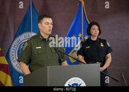Border Patrol Tucson Sektor Chief Rodolfo Karisch spricht an der Gemeinsamen CBP und DOD Briefing zum Betrieb sichere Leitung im Hafen von Nogales am 9. November 2018. Die Tucson Direktor der Feldeinsätze Petra Horne ist zu seinem Recht. Zoll- und Grenzschutz Stockfoto