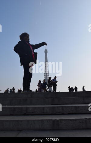 Silhouetten von Touristen posieren für Fotos mit dem Eiffelturm im Hintergrund am Trocadero Paris, Frankreich Stockfoto