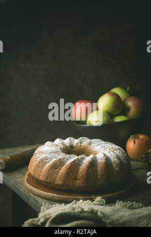 Landhausstil Apple Bundt Cake bestreut mit Puderzucker auf alten Holztisch Stockfoto