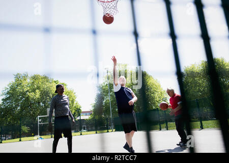 Aktive ältere Männer Basketball spielen im sonnigen Park Stockfoto