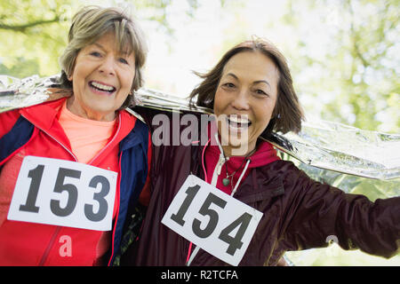 Porträt Lächeln, zuversichtlich Active Senior Frauen beenden Sport Rennen, in thermische Decke gewickelt Stockfoto