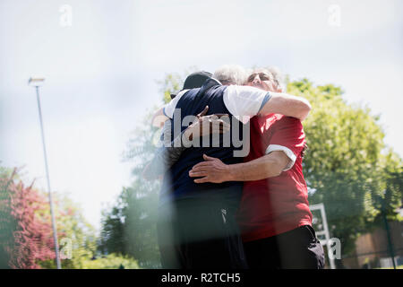 Aktive ältere Männer Freunde umarmen im sonnigen Park Stockfoto