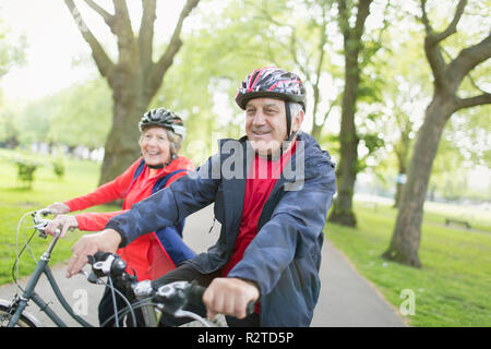 Active Senior paar Reiten Fahrräder in Park Stockfoto