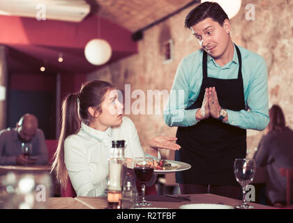 Weibliche client Unmut Ausdruck mit Essen sprechen zu entschuldigen, Kellner. Fokus auf Frau Stockfoto