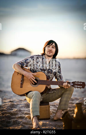 Junger Mann mit Gitarre am Strand Stockfoto