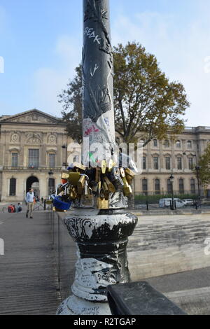 Liebe Schloss auf dem Steg Pont des Arts auf dem Fluss Seine und Menschen zu Fuß über eine Fußgängerbrücke über den RiverSeine mit Blick auf den Louvre. Stockfoto