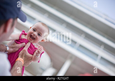 Porträt eines lachenden Jungen baby aloft von ihrem Vater gehalten wird. Stockfoto